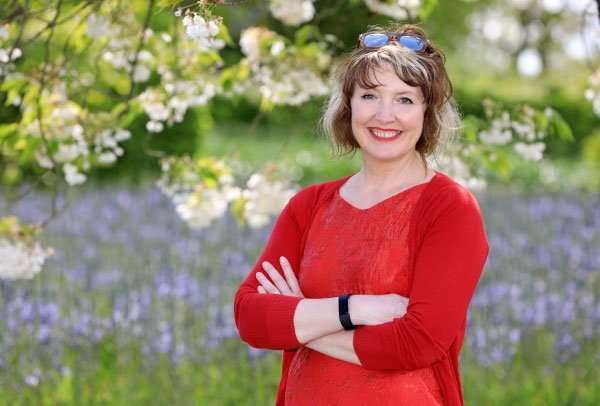 Ann-Marie Powell in her Hampshire garden, sitting on timber steps holding sweet peas